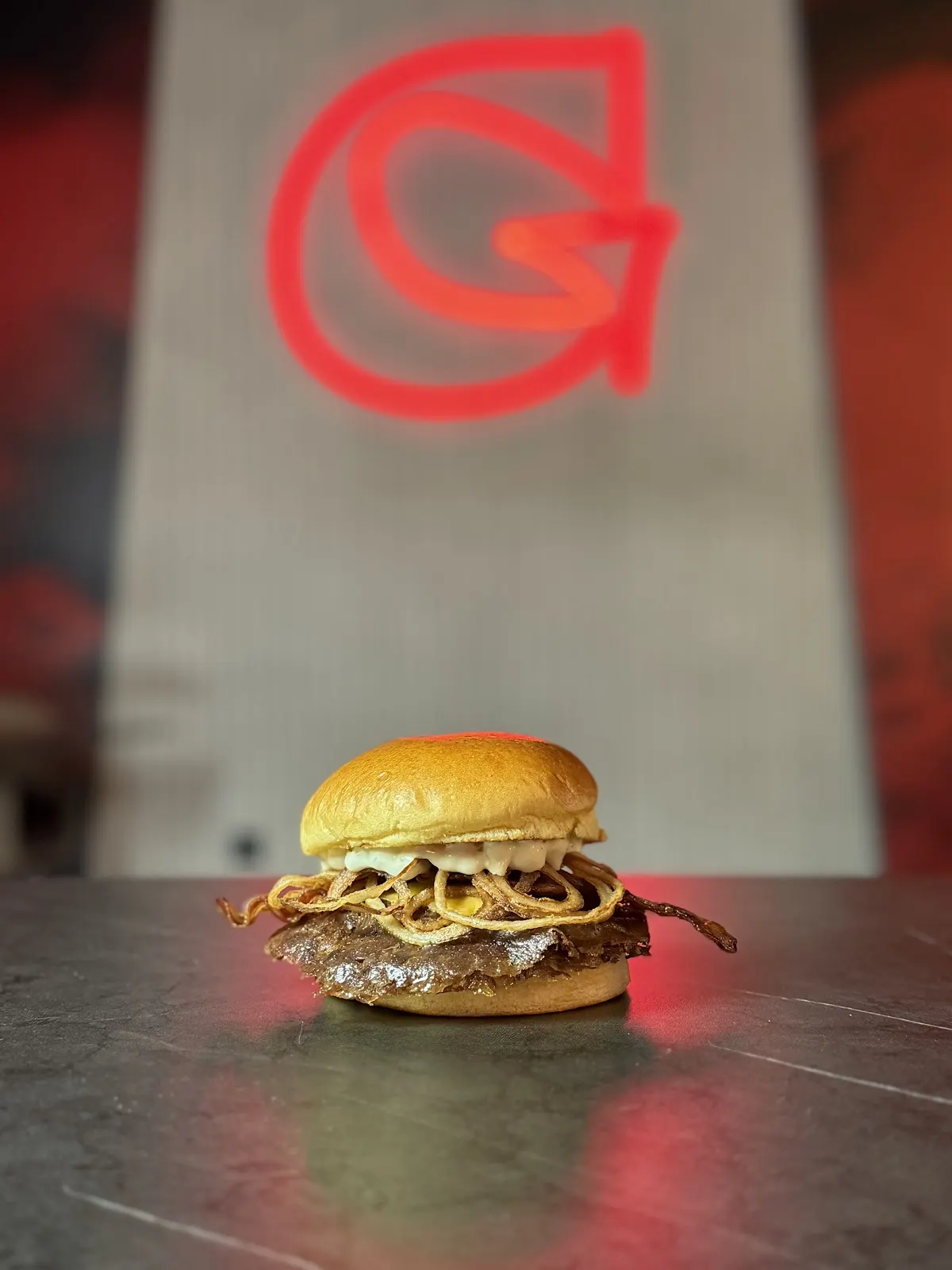 Burger servi à côté du logo de GULA SUPREME