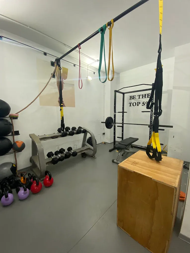Espace musculation avec TRX, kettlebells et cage de poids libres chez Soriano Trainers