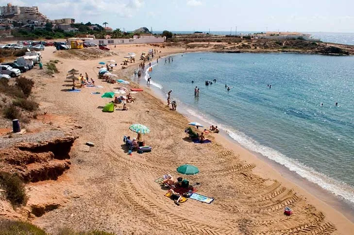 Swimmers and colourful parasols on the golden sand of Cala Reona, in Cabo de Palos