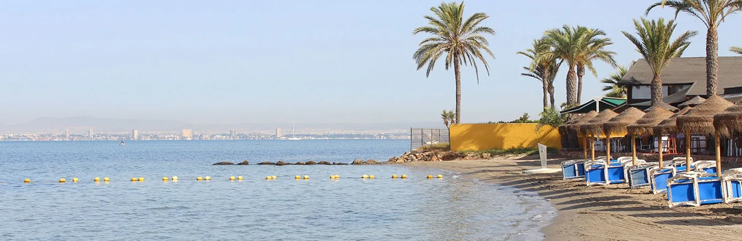 Parasols and palms at Playa Chica beside the calm waters of Mar Menor