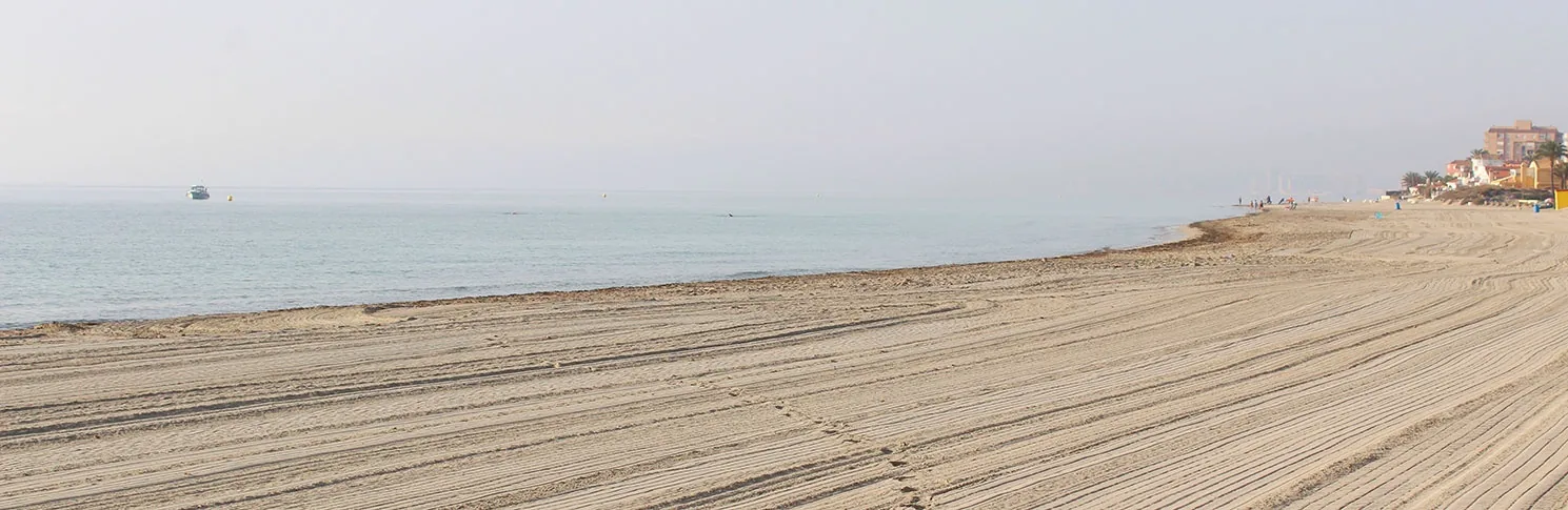 Wide stretch of raked sand at Playa del Estacio, with calm Mediterráneo waters early in the morning