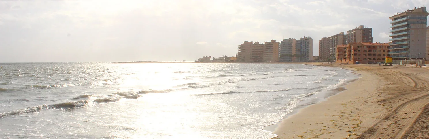 Playa del Estacio shoreline at dawn, with waves on Mediterráneo and buildings in La Manga in the background