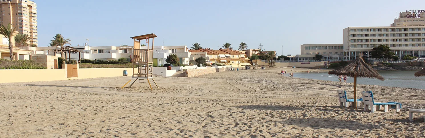 Tour de sauveteur sur le sable de Playa Galúa, avec les parasols et les immeubles derrière
