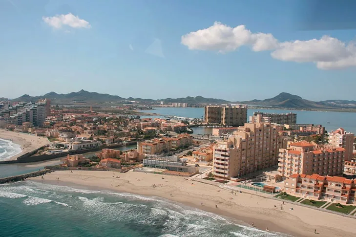 Vue aérienne de La Manga au niveau de Playa Galúa, avec le Mediterráneo, les immeubles et la montagne au fond
