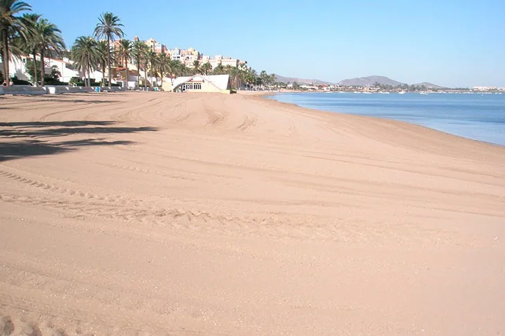 Raked sand at Playa Honda, with the promenade, white buildings and palms on one side and Mar Menor on the other