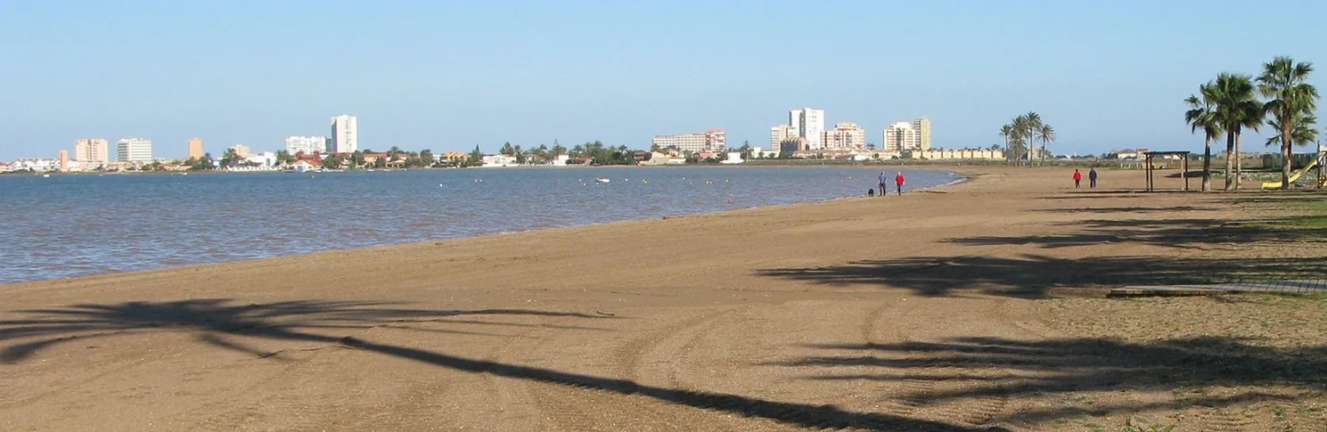 Playa Honda coastline with wet sand in the foreground and the skyline of La Manga in the distance