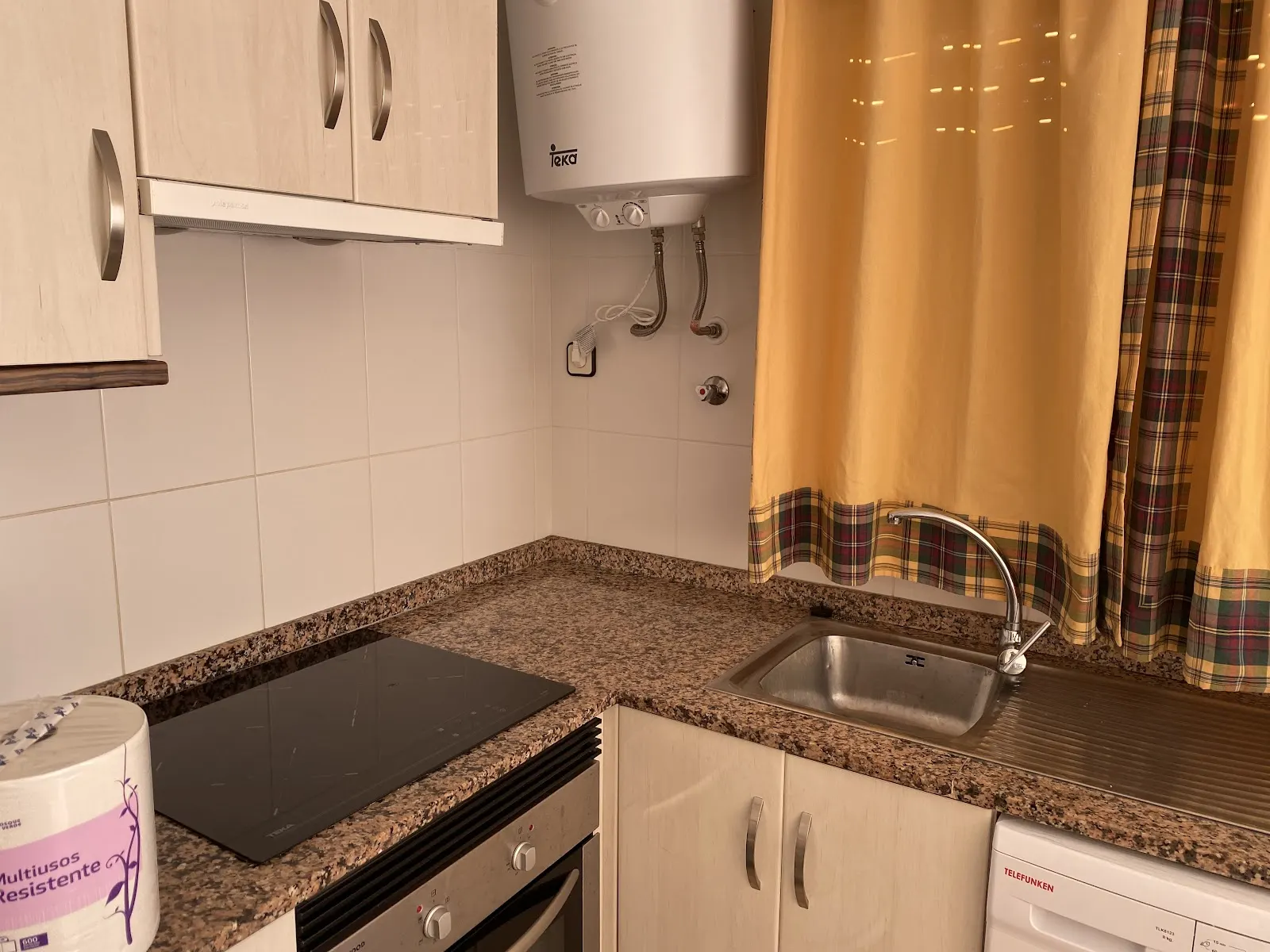 Ausgestattete Küche mit Glaskeramikkochfeld und Warmwasserboiler in einem Apartment im Olympia Center