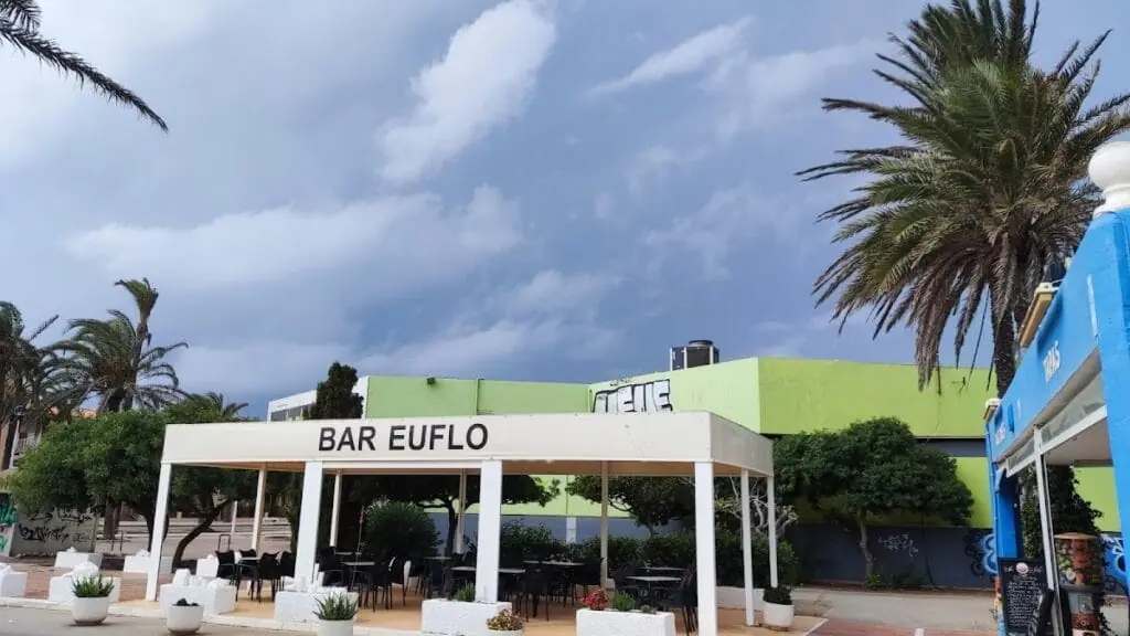 Überdachte Terrasse der Bar Euflo unter bewölktem Himmel