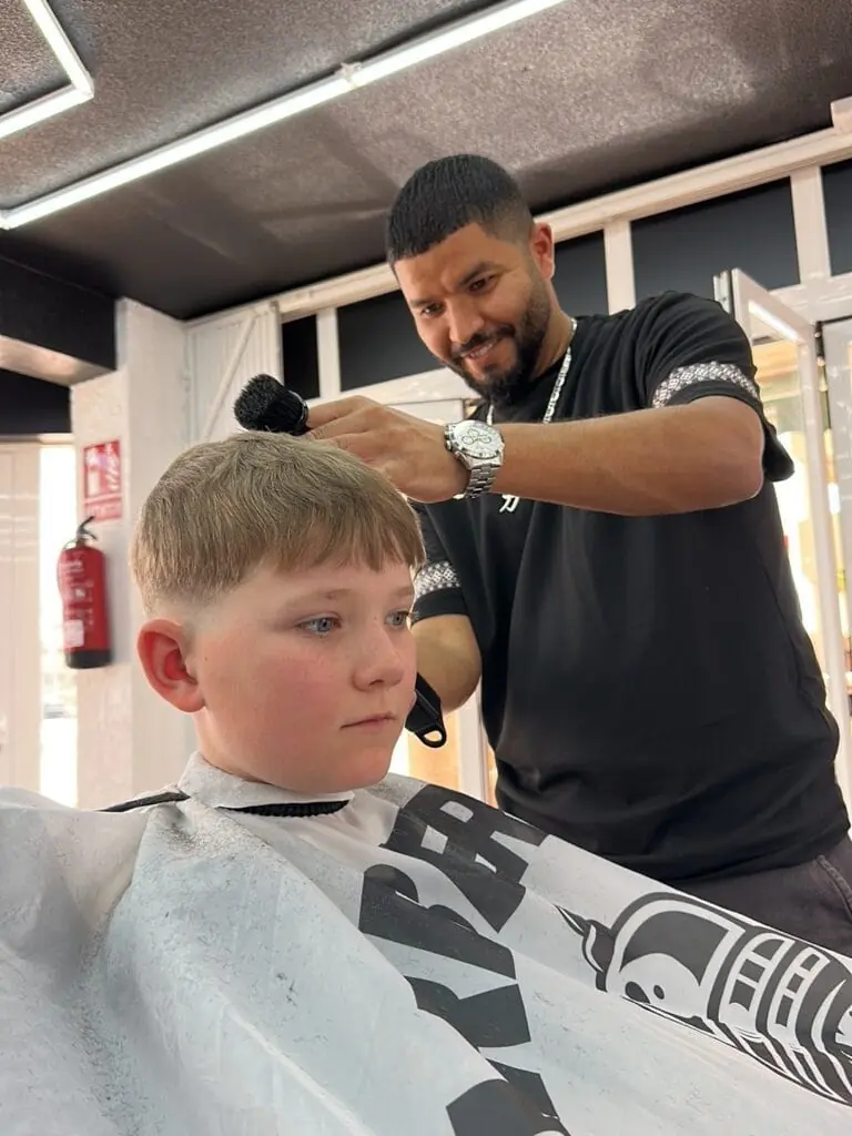Barber cutting a child's hair at Issan The Black