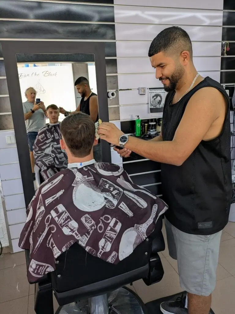 Barber tidying a customer's haircut in front of the mirror at Issan The Black