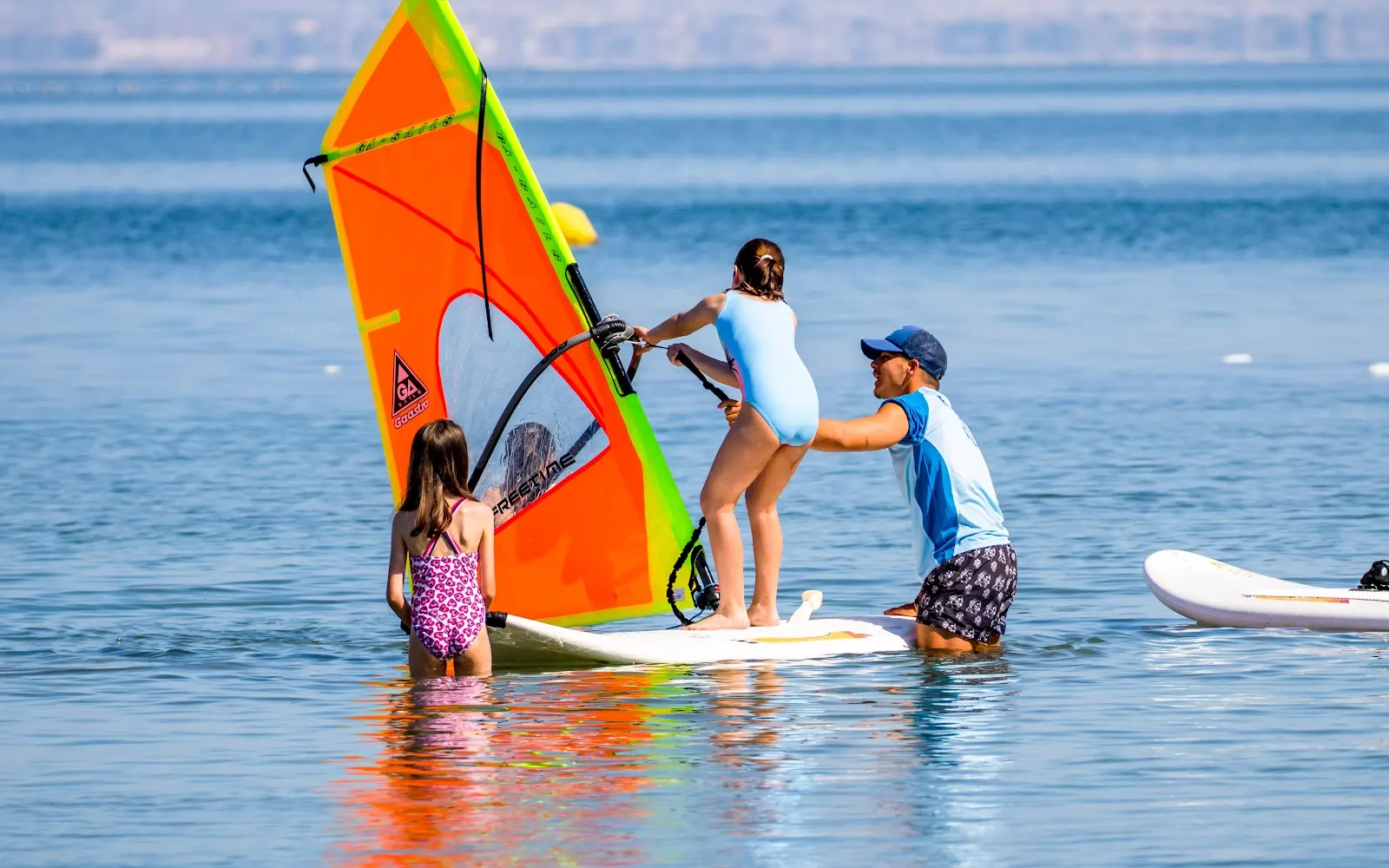Moniteur aidant une fillette à faire de la planche à voile au Campus Náutico Dacar