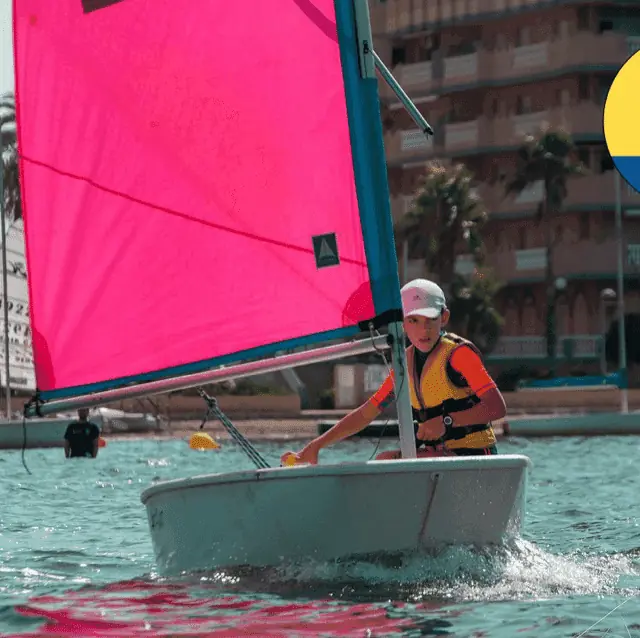 Enfant naviguant sur un Optimist à voile rose à Escuela de Vela Sandrina