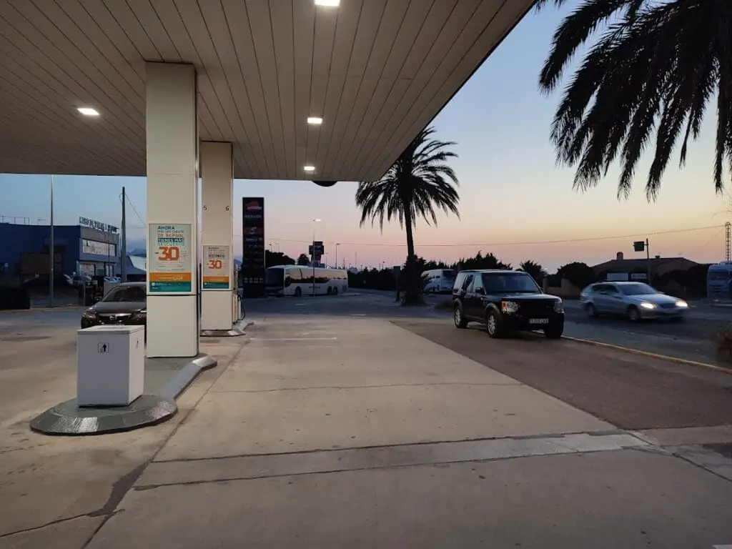 Pompes de la Estación de Servicio Repsol au coucher du soleil, avec un palmier près de l'accès