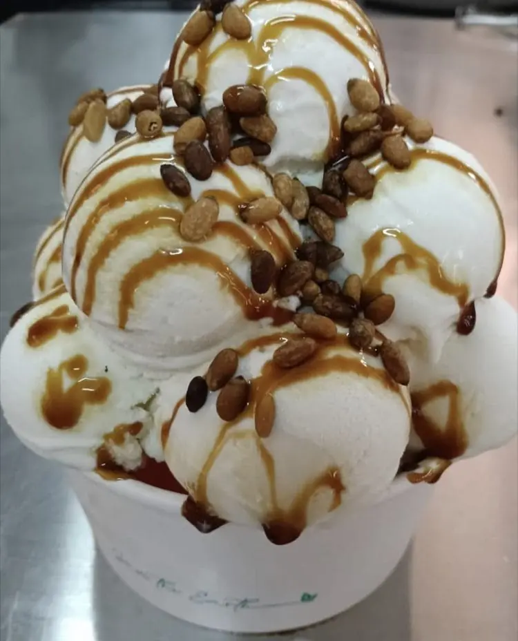Becher mit handwerklichem Eis, Pinienkernen und Karamellsauce bei Fábrica de Helado Artesano Verdú