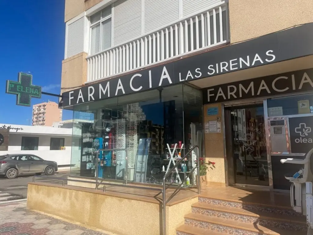 Front of Farmacia Las Sirenas with its illuminated green cross, in La Manga