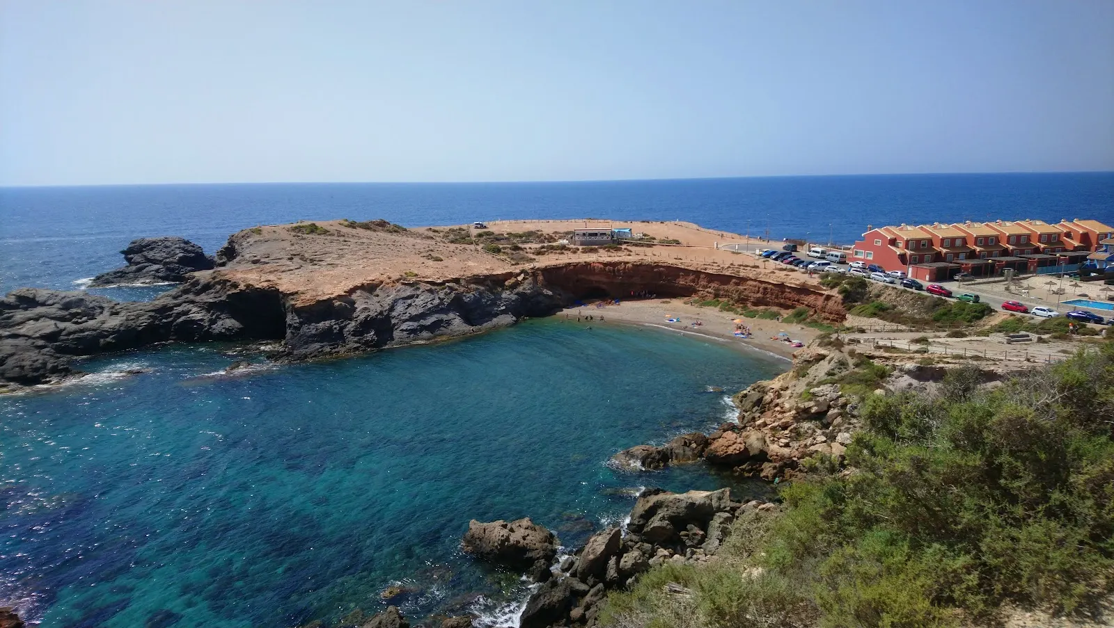 Bucht mit türkisfarbenem Wasser am Kap, mit roten Häusern im Hintergrund