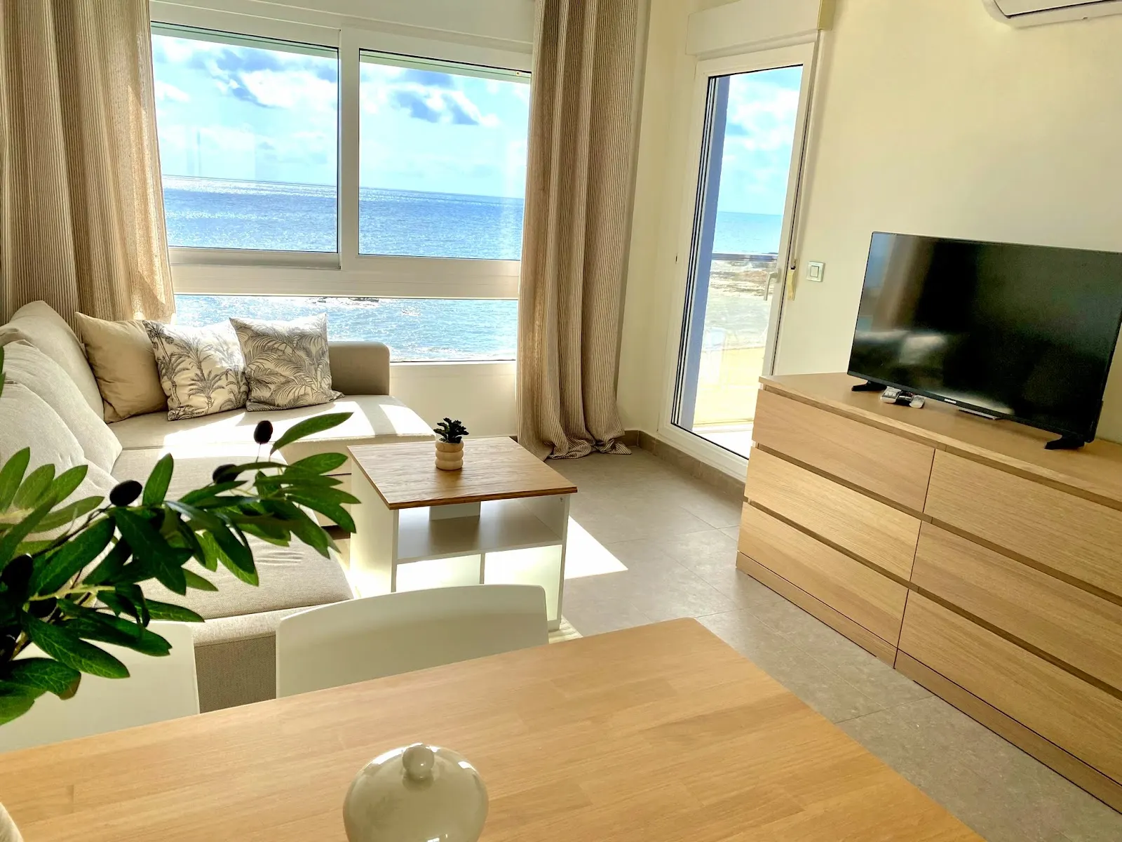 Apartment living room with a sofa, television and large window overlooking the sea