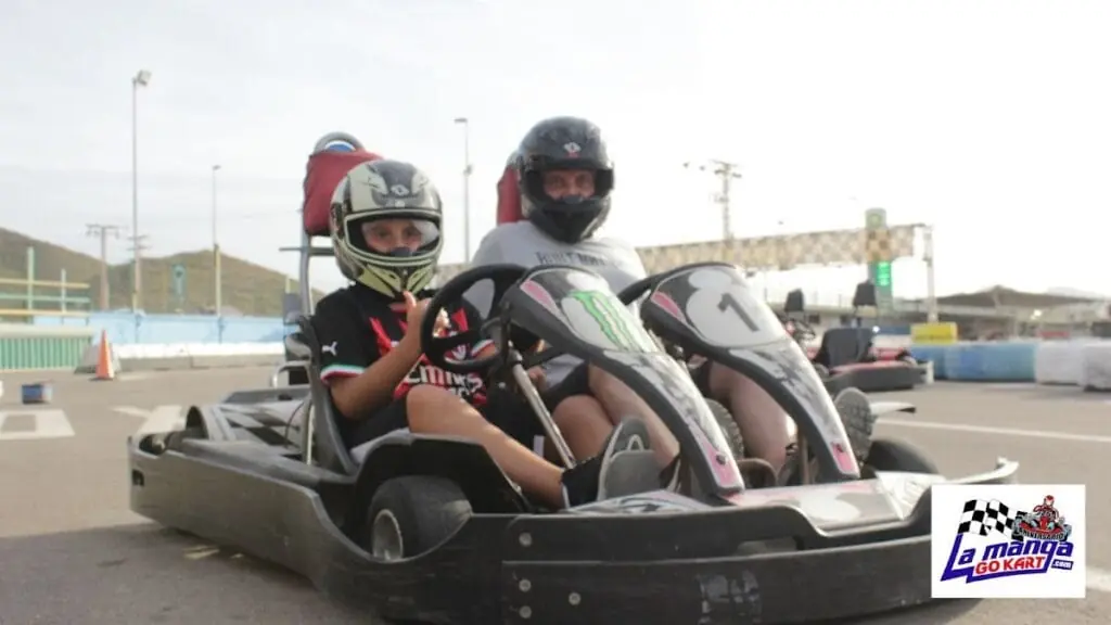 Zwei Kinder mit Helm in einem Zweisitzer-Kart auf der Strecke von La Manga Gokart