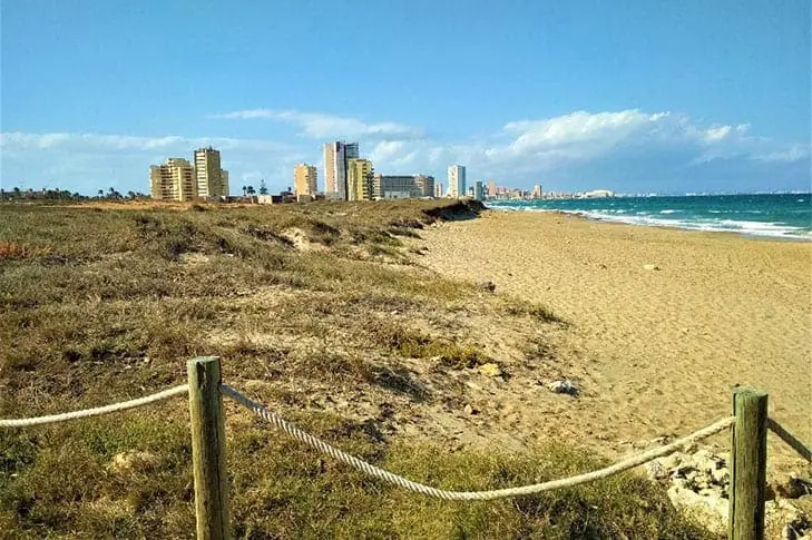 Beach and dunes of Las Amoladeras with the buildings of La Manga in the background