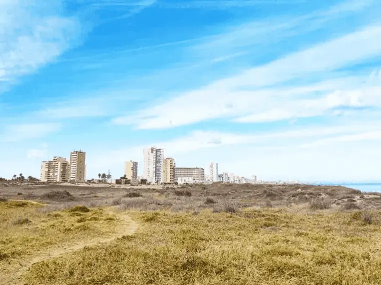 Plain of dry scrub with the buildings of La Manga in the background
