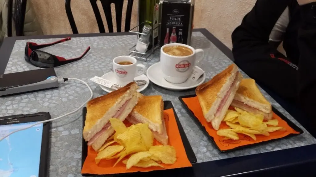 Montaditos jambon-fromage et deux cafés servis sur une table