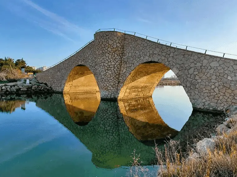Bögen der Puente de la Risa, die sich im Wasser spiegeln