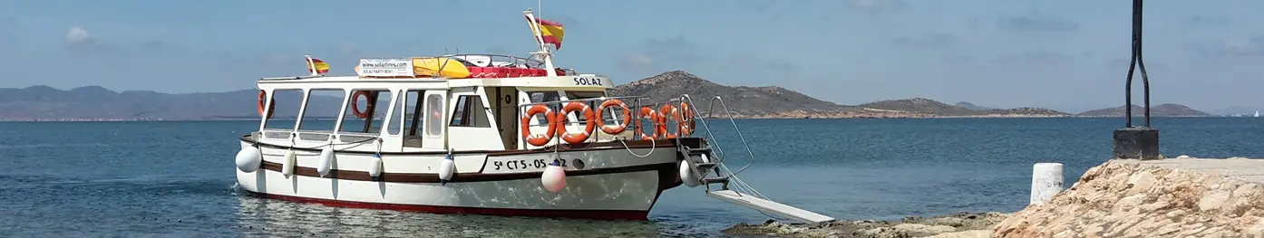 Das Boot Solaz liegt am Ufer vertäut, im Hintergrund die Berge