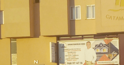 Cartel de Administración de Fincas Costa Cálida en fachada de edificio amarillo en La Manga del Mar Menor