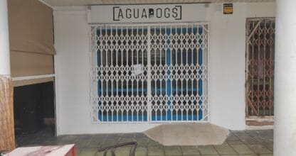 Fachada cerrada de AguaDogs con reja metálica y rótulo sobre la puerta en La Manga del Mar Menor