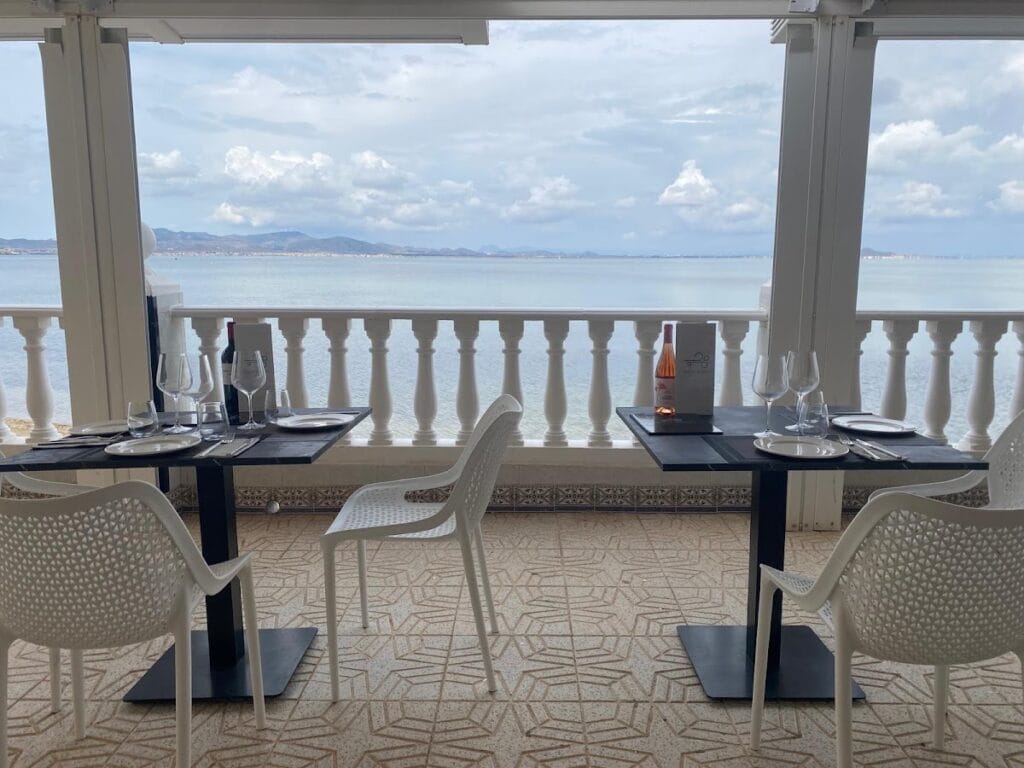Terraza acristalada de Aires de Jaloque con mesas preparadas y vistas panorámicas al Mar Menor