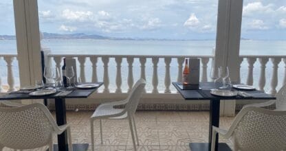 Terraza acristalada de Aires de Jaloque con mesas preparadas y vistas panorámicas al Mar Menor