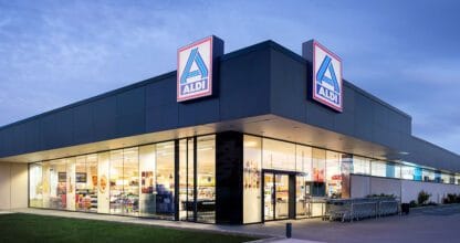 Fachada exterior del supermercado ALDI en La Manga del Mar Menor iluminada al atardecer con doble rótulo luminoso