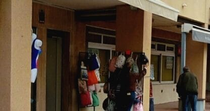 Fachada de Aloha Moda y Complementos en La Manga del Mar Menor con rótulo negro y ropa y bolsos expuestos en el exterior