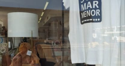 Escaparate de tienda con camiseta blanca SOS Mar Menor y artículos de decoración del hogar en La Manga del Mar Menor