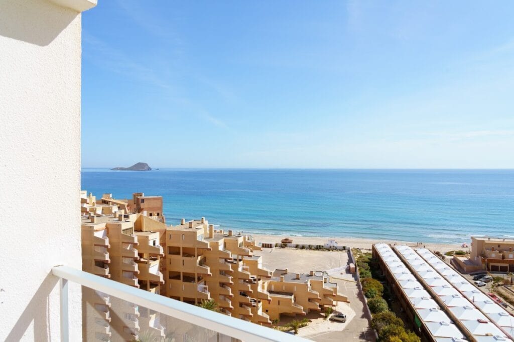 Vista panorámica desde el balcón del AluaSun Doblemar en La Manga del Mar Menor, con playa de arena, mar azul turquesa e isla al fondo