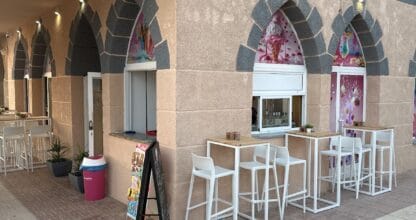 Terraza exterior de AMONET Heladería y Coctelería en La Manga del Mar Menor con mesas altas blancas bajo arcos decorados