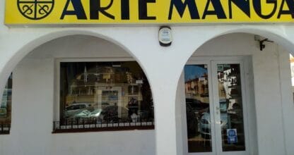 Fachada de tienda Arte Manga con gran rótulo amarillo y negro sobre edificio blanco de arcos en La Manga del Mar Menor
