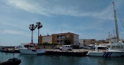 Puerto pesquero de Cabo de Palos con barcos amarrados, velero y edificios residenciales junto al mar