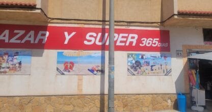 Exterior del Bazar y Super 365 Días con letrero rojo y carteles de artículos de playa y hogar, La Manga