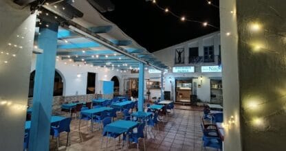 Terraza nocturna de Bella Napoli con mesas azules, guirnaldas de luces y letrero de ristorante pizzería en La Manga