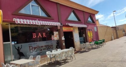 Fachada rosa del Bollywood Indian Restaurant con terraza y mesas blancas en la acera, La Manga del Mar Menor