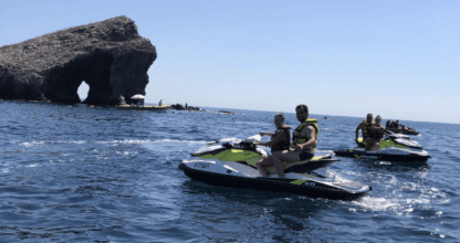 Dos motos de agua navegando frente a un arco de roca en el mar con Bonds Jet Ski Rental, La Manga del Mar Menor