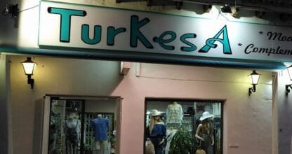Fachada iluminada de noche de Turkesa moda y complementos con maniquíes en los escaparates, La Manga