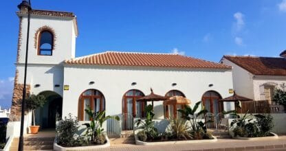 Casa blanca de estilo mediterráneo con arcos y sombrillas de palma en Cabo de Palos con Encanto, Cabo de Palos, Murcia