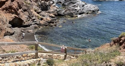 Escaleras de madera hacia la Cala Roja (Cala de la Escalerica) con aguas cristalinas y rocas rojizas en Cabo de Palos