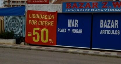 Local comercial en La Manga del Mar Menor con carteles de artículos de playa y hogar y liquidación por cierre al cincuenta por ciento