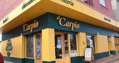 Fachada amarilla y verde de Carnicería El Carpio con rótulo 'desde 1969' y pizarra de ofertas, La Manga del Mar Menor