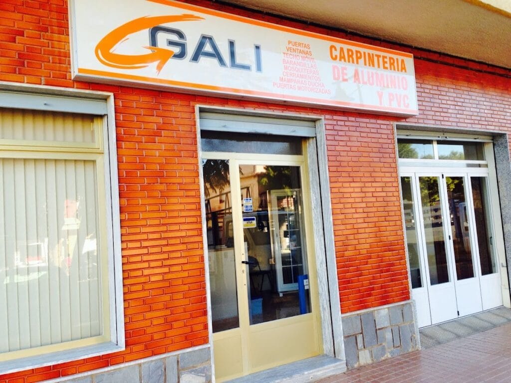 Fachada con rótulo naranja de Gali Carpintería de Aluminio y PVC en edificio de ladrillo, La Manga del Mar Menor
