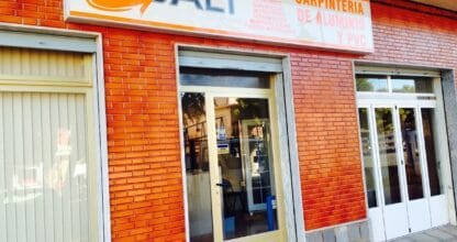 Fachada con rótulo naranja de Gali Carpintería de Aluminio y PVC en edificio de ladrillo, La Manga del Mar Menor
