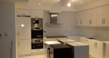 Cocina moderna con muebles blancos e isla instalada por Carpintería Juan Huertas Martínez, La Manga del Mar Menor